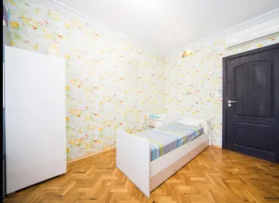 a childs bedroom with a white bed and floral wallpaper at Tsarigradska in Burgas City