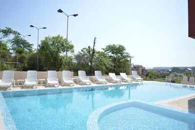 a large swimming pool with lounge chairs and a poolside at Hotel Ray in Sozopol