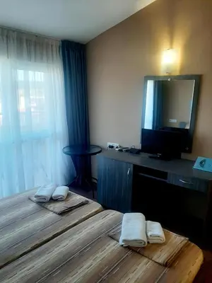 a hotel room with two beds and a flat screen tv at Hotel Ray in Sozopol