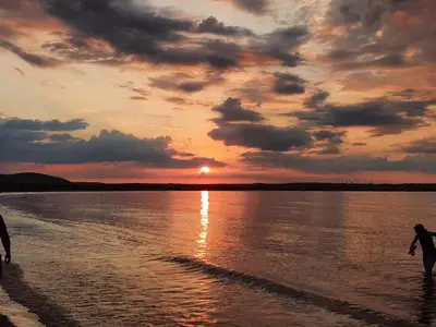 two people walking on the beach at sunset at Eve Santa Marina Apartments - sea, pools, relax in Sozopol