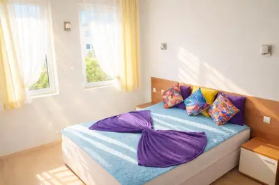 a bedroom with a bed with purple sheets and pillows at Sunset Dream Polo Resort in Sunny Beach