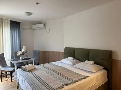a bedroom with a bed and a table with a chair at Студио ''Сарафово'' на първа линия in Burgas City
