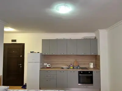 a kitchen with white cabinets and a white refrigerator at Студио ''Сарафово'' на първа линия in Burgas City