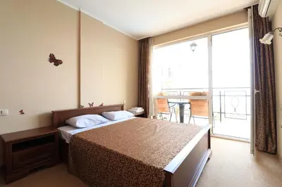 a hotel room with a bed and a balcony at Първа линия Апартаменти in Pomorie