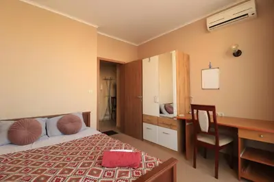 a bedroom with a bed and a desk and a desk at Първа линия Апартаменти in Pomorie