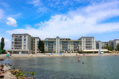 a group of people in the water in front of a beach at Първа линия Апартаменти in Pomorie