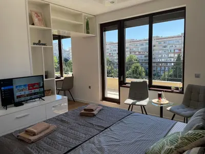 a bedroom with a large bed with a flat screen tv at Studio Rêve in Burgas City