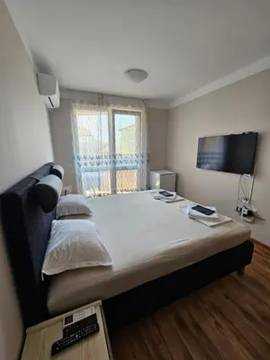 a bedroom with a large bed and a television at Apartments Vilma&Villiam in Ravda