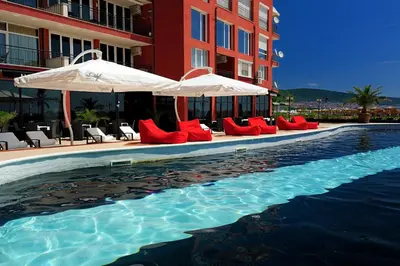 a pool with chairs and umbrellas next to a building at Heaven Lux Apartments in Sunny Beach