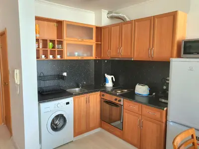 a kitchen with wooden cabinets and a washing machine at Sveti Vlas Marina Beach Apartment - Vega Village in Sveti Vlas
