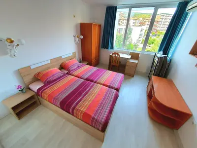 a bedroom with a bed and a desk and a window at Sveti Vlas Marina Beach Apartment - Vega Village in Sveti Vlas