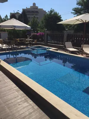 a swimming pool with chairs and an umbrella at The White Houses Complex in Nesebar