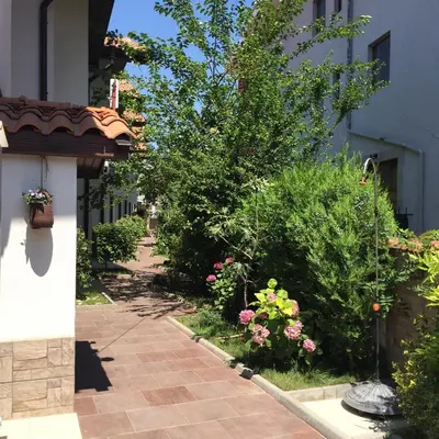 a walkway through a garden with flowers and plants at The White Houses Complex in Nesebar