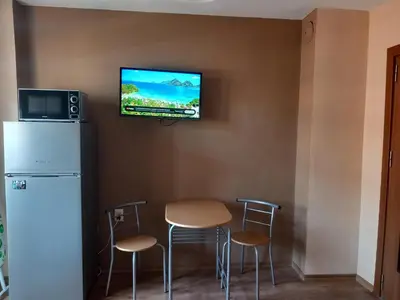 a room with a refrigerator and a tv on a wall at Апартамент Морски оазис in Burgas City