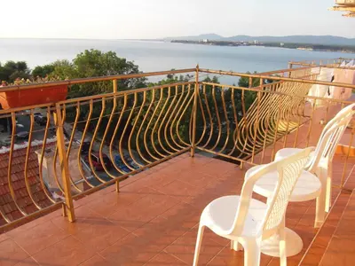 two white chairs sitting on a balcony overlooking the water at Kostovi Primorsko in Primorsko