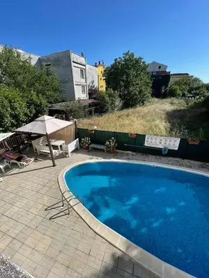 a large blue swimming pool with an umbrella and a patio at Villa Flora SP apartments in Ravda