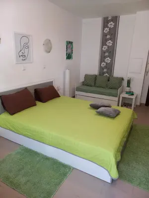 a bedroom with a large bed with a green blanket at Венета 1 in Sozopol