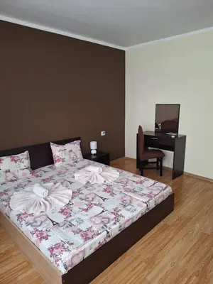 a bedroom with a large bed with a desk and a chair at Къща за гости Симеонови in Sozopol