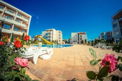 a pool with a slide and some flowers and buildings at 1-bedroom Apartment in a Resort with 6 Pools, Top Floor, Stunning Sunset View in Sunny Beach