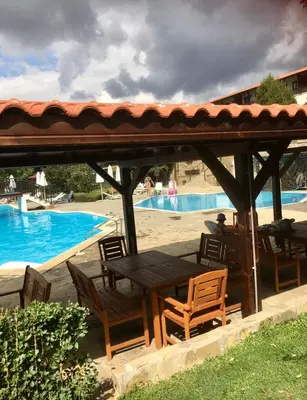 a wooden table and chairs under a gazebo by a pool at Complex Monastery 1 -Marina Dinevi -Saint Vlas in Sveti Vlas