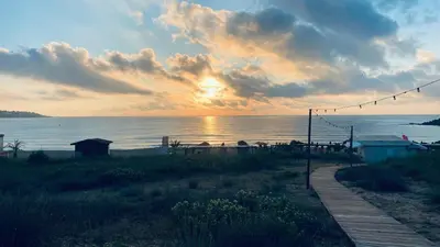 a sunset on the beach with the sun setting over the water at Свети Йоан in Sozopol