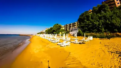 a beach with white lounge chairs and the ocean at William's apartments - fourth pretty studio in Sveti Vlas