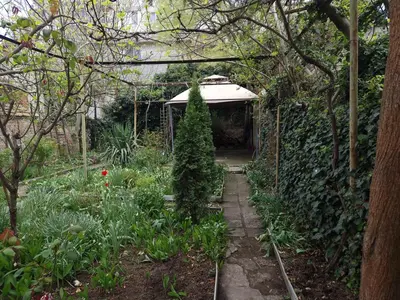 a garden with a pathway leading to a house at Етаж от къща с двор in Burgas City