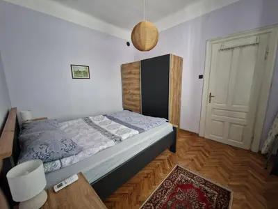 a bedroom with a bed and a table and a door at Етаж от къща с двор in Burgas City