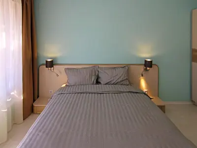 a bed in a bedroom with two lights on the wall at Premium Apartment Villa Aristo in Sveti Vlas
