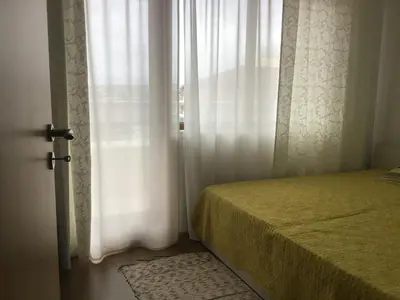 a bedroom with a bed and a window with white curtains at Casa del Mar Apartment in Obzor