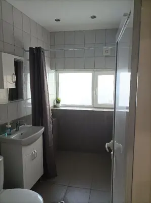 a bathroom with a shower and a sink and a window at Apartment Starfish in Varna City
