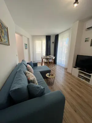 a living room with a blue couch and a table at Azzurro Premium Apartment on Bulevard Bogoridi in Burgas City