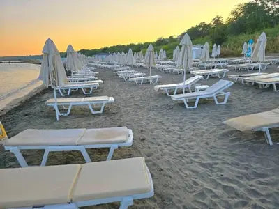 a group of lounge chairs and umbrellas on a beach at Viriks in Burgas City