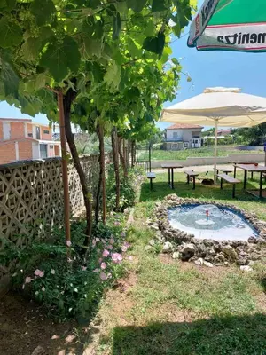 a garden with a pond and benches and an umbrella at Krimski Guest House and Bungalows in Byala
