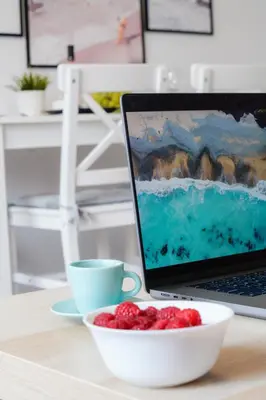 a laptop computer sitting on a table with a bowl of berries at Central Cosy, Fully Renovated 2BD Near the Cathedral in Varna City
