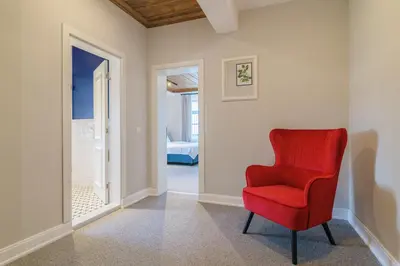 a red chair in a hallway with a bedroom at Carpe Diem in Sladka Voda