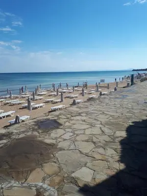 a beach with chairs and people on the water at Evridika Apartments in Nesebar