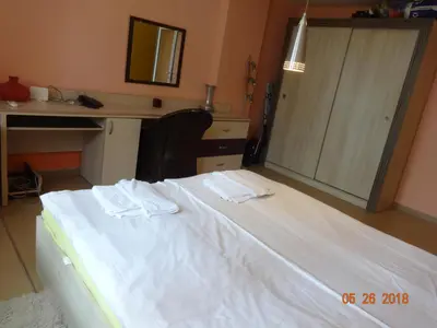 a bedroom with a white bed with a desk and a mirror at Evridika Apartments in Nesebar
