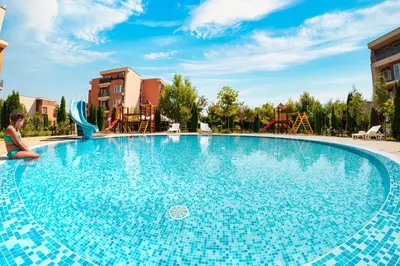 a large blue swimming pool with a girl sitting on it at Nessebar and Holiday Fort Apartments in Sunny Beach