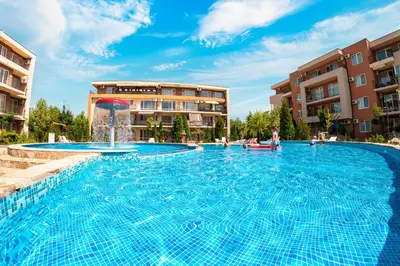 a large swimming pool with a fountain in front of buildings at Nessebar and Holiday Fort Apartments in Sunny Beach