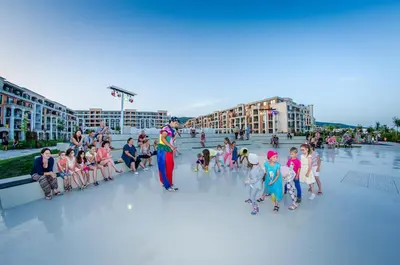a group of children sitting around a man in a crowd at Premier Fort Beach Resort in Sunny Beach
