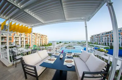 a patio with a table and chairs on a balcony at Premier Fort Beach Resort in Sunny Beach