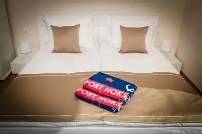 a white bed with two pillows and a sign on it at Premier Fort Beach Resort in Sunny Beach