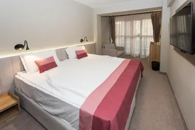 a bedroom with a large bed and a television at Grand Hotel Sunny Beach - All Inclusive in Sunny Beach
