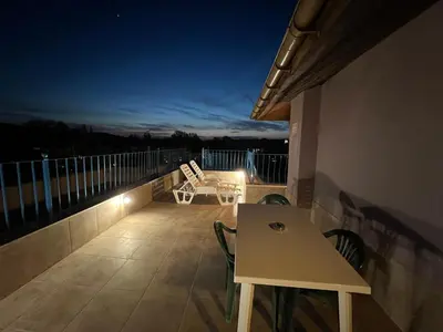 a patio with a table and chairs on a balcony at night at Camping Gradina Garden Beach b33 in Chernomorets
