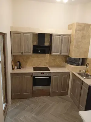 a kitchen with wooden cabinets and a stove top oven at Апартаменти Стефанов in Varna City