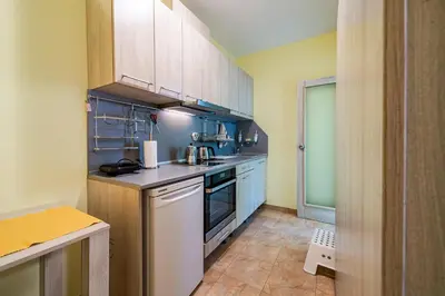 a small kitchen with white cabinets and blue walls at Sunny and Quiet 2bdr Central Apartment in Varna City