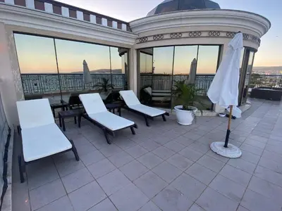 a patio with white chairs and an umbrella on a roof at Penthouse Happy Moments in Sunny Beach