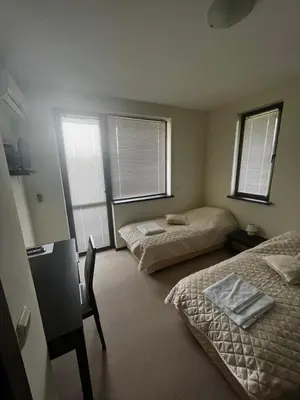 a bedroom with two beds and two windows at Велика Гардън - Акация 6 in Lozenets