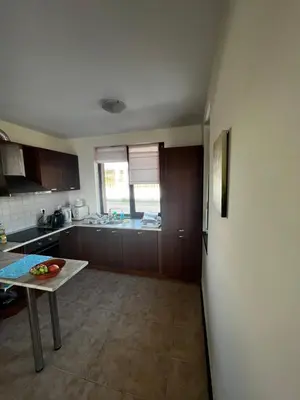 a kitchen with a table in the middle of a room at Велика Гардън - Акация 6 in Lozenets